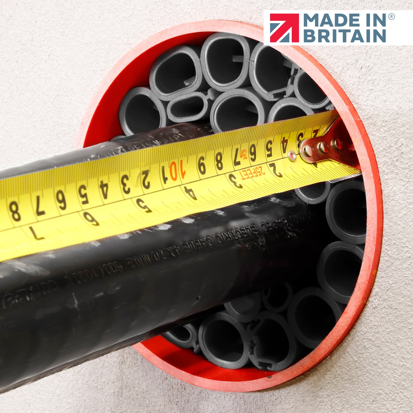 Close-up of black cable ducts with a yellow measuring tape inside a red-sealed duct opening, showcasing DuctSeal FR fire-rated sealing system with 'Made in Britain' logo.