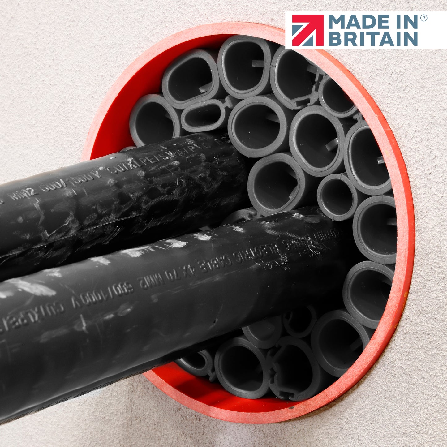 Close-up of black cable ducts with a yellow measuring tape inside a red-sealed duct opening, showcasing DuctSeal FR fire-rated sealing system with 'Made in Britain' logo.