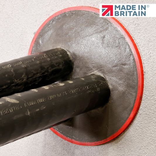 Two black pipes sealed with GreyStuff fire-resistant duct seal; smooth grey plug with red edge and a Made in Britain logo in the corner
