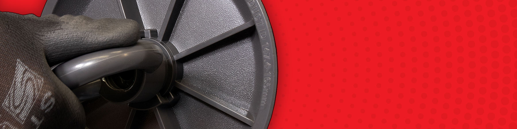 Gloved hand tightening a grey duct plug on a red background